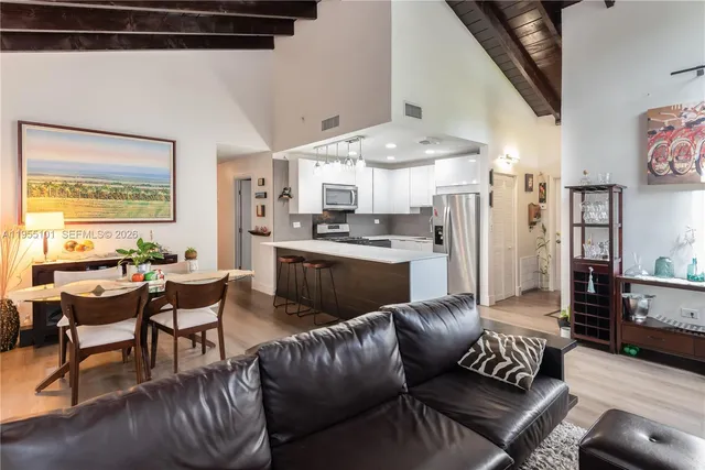 a living room with furniture kitchen view and a large window