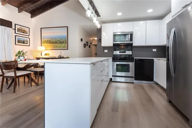 a kitchen with stainless steel appliances granite countertop a refrigerator a stove top oven a sink dishwasher a dining table and chairs with wooden floor