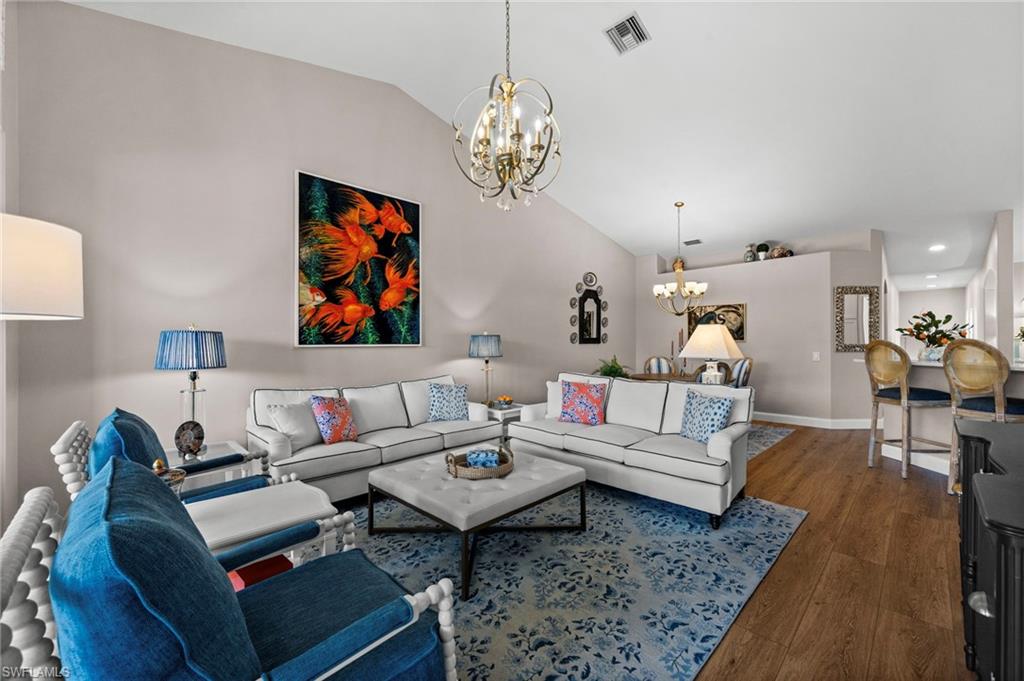 9331 Spring Run Boulevard, Unit 3005 Estero, FL 34135 - Photo 18 of 48 Vaulted ceiling great room with wood-finish flooring, a tiered chandelier, and a breakfast bar with seating