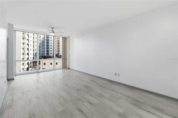 a view of an empty room with wooden floor and a window