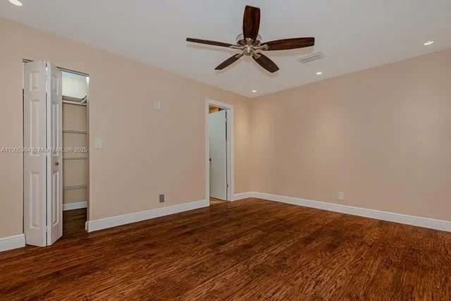 a view of room with wooden floor and a ceiling fan
