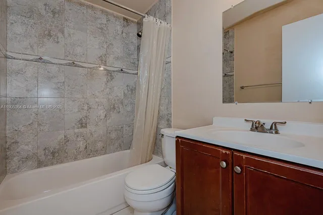 a bathroom with a granite countertop bathtub shower sink vanity and toilet