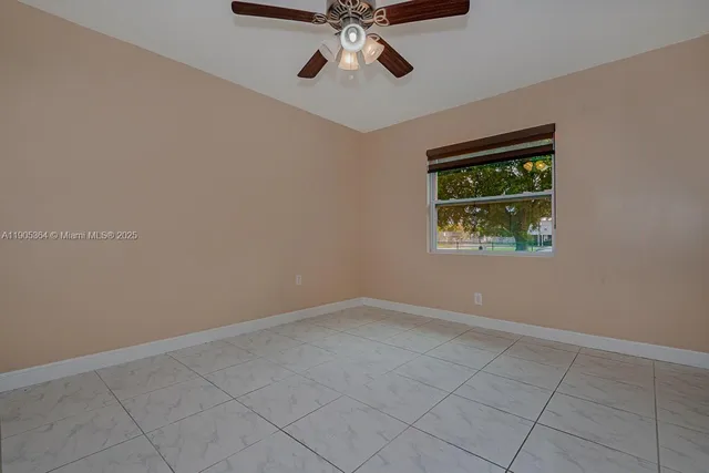 an empty room with chandelier fan and windows