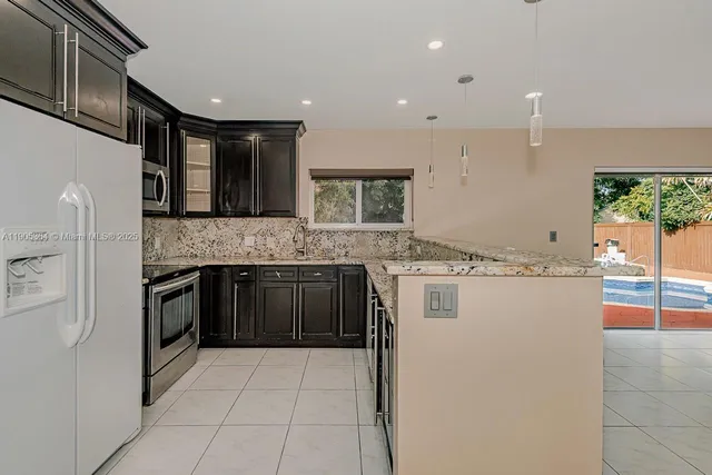 a kitchen with stainless steel appliances granite countertop a stove a sink and a refrigerator