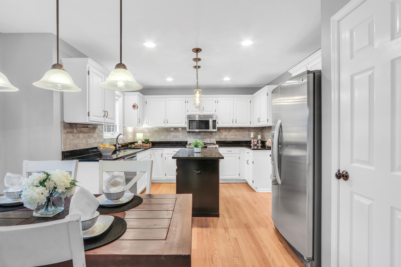 310 Concord Square Gurnee, IL 60031 - Photo 16 of 46 a kitchen with stainless steel appliances granite countertop a refrigerator a sink dishwasher a stove and a dining table with wooden floor