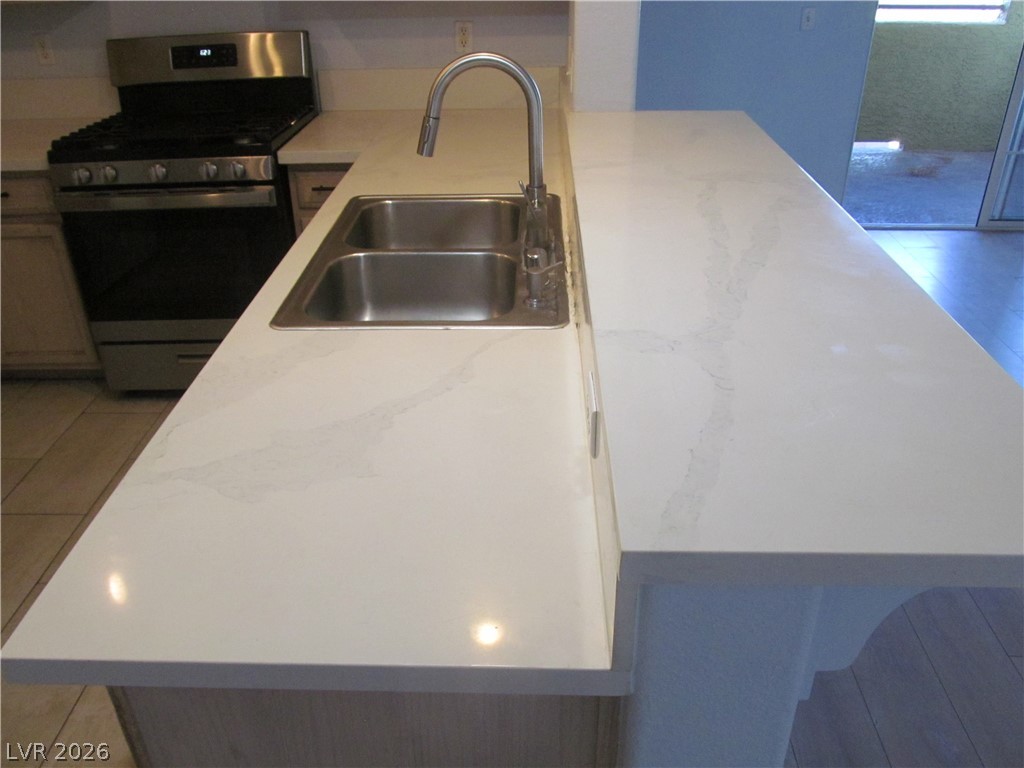 7950 West Flamingo Road, Unit 2048 Las Vegas, NV 89147 - Photo 9 of 24 A spacious kitchen island boasts sleek white countertops and a double basin sink.