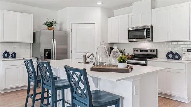 a kitchen with stainless steel appliances granite countertop a dining table and chairs