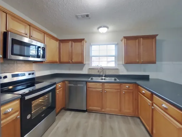 a kitchen with stainless steel appliances granite countertop wooden cabinets stove top oven and sink