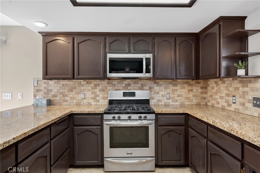 2097 Fallbrook Court Paso Robles, CA 93446 - Photo 14 of 65 a kitchen with granite countertop a stove a sink and a microwave
