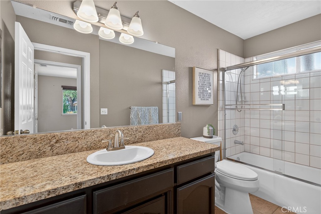 2097 Fallbrook Court Paso Robles, CA 93446 - Photo 30 of 65 a bathroom with a granite countertop sink a toilet a mirror and shower