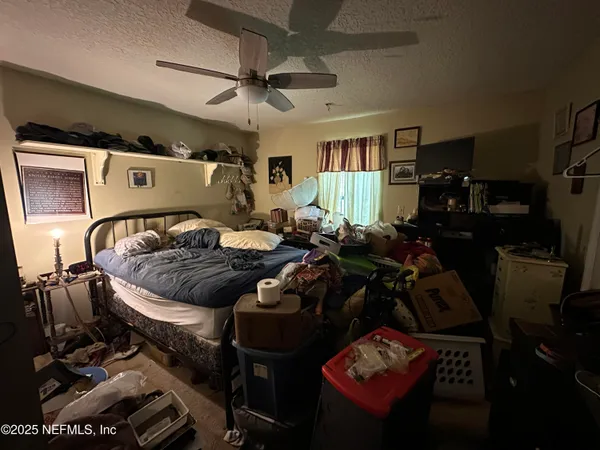 a bed room with a bed a couch and a ceiling fan
