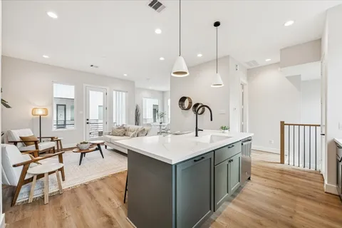 a room with lots of white furniture a sink dishwasher and a dining table with wooden floor