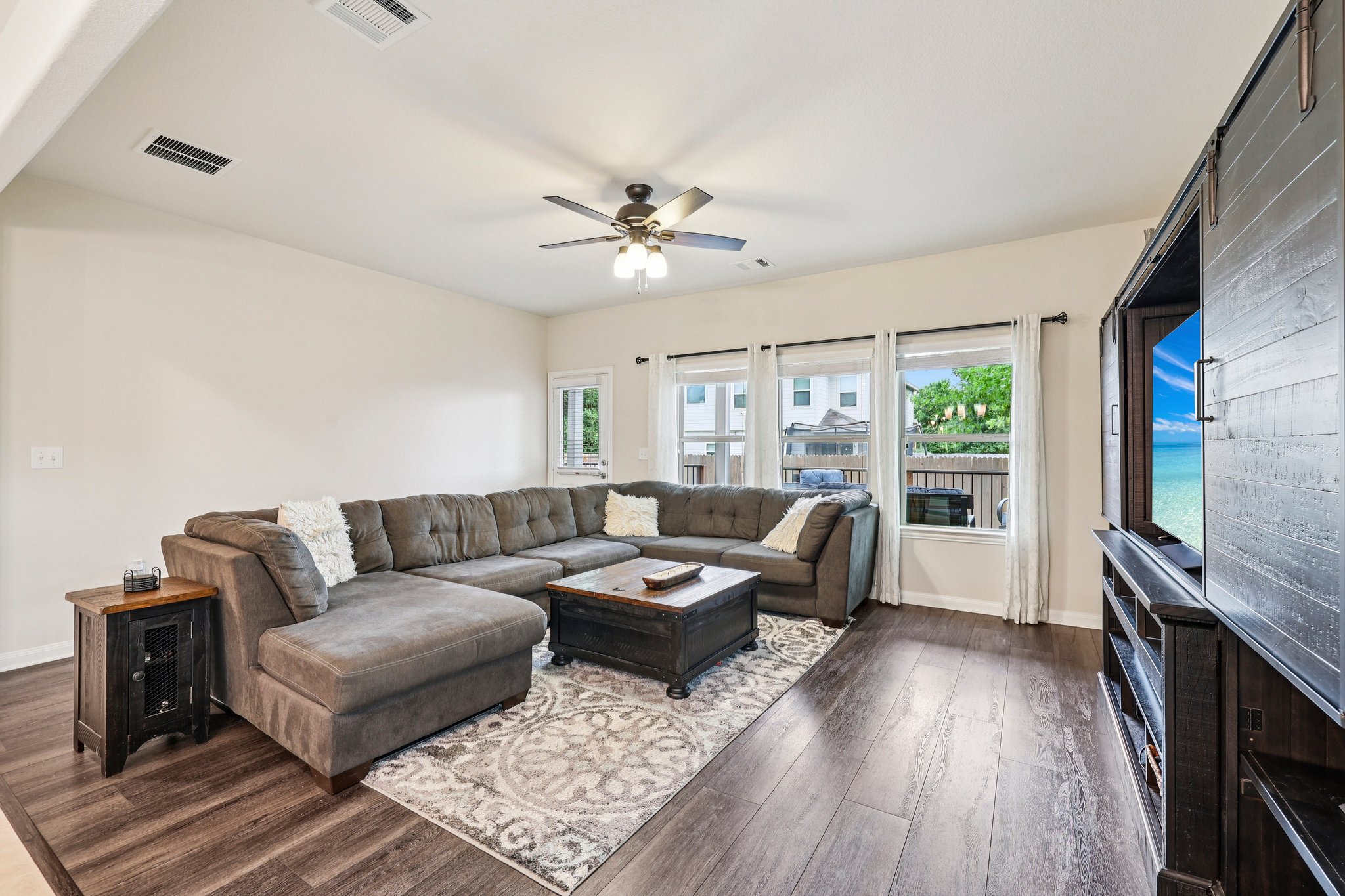 10033 Gertrudis Loop Austin, TX 78747 - Photo 12 of 39 The living area features wood-look flooring, a ceiling fan, and large windows that provide abundant natural light