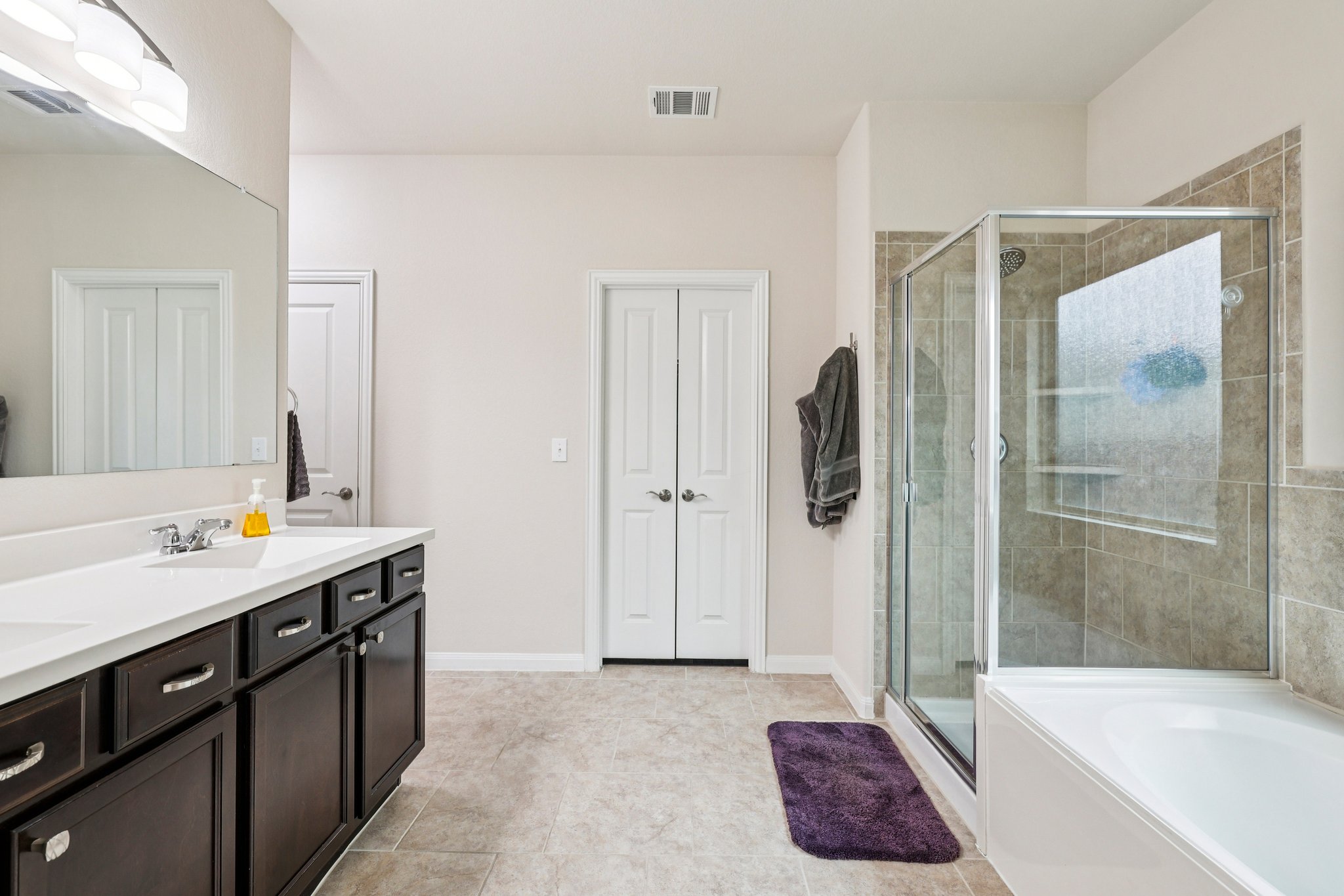 10033 Gertrudis Loop Austin, TX 78747 - Photo 15 of 39 Bathroom featuring a double vanity with dark wood cabinetry, a tiled shower, and a separate bathtub
