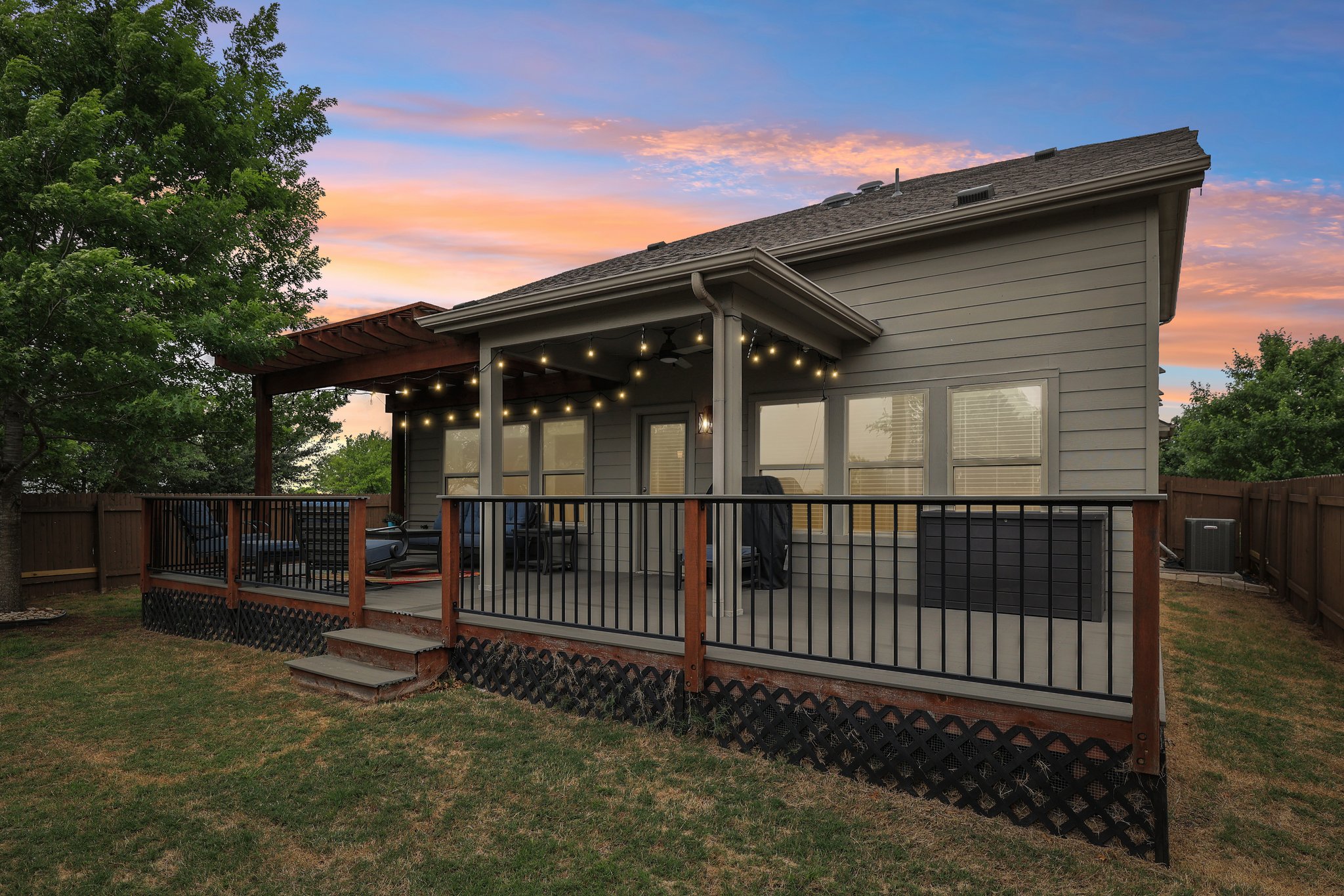 10033 Gertrudis Loop Austin, TX 78747 - Photo 2 of 39 The property features a spacious elevated deck with a pergola, string lights, and black railings, offering an inviting outdoor space