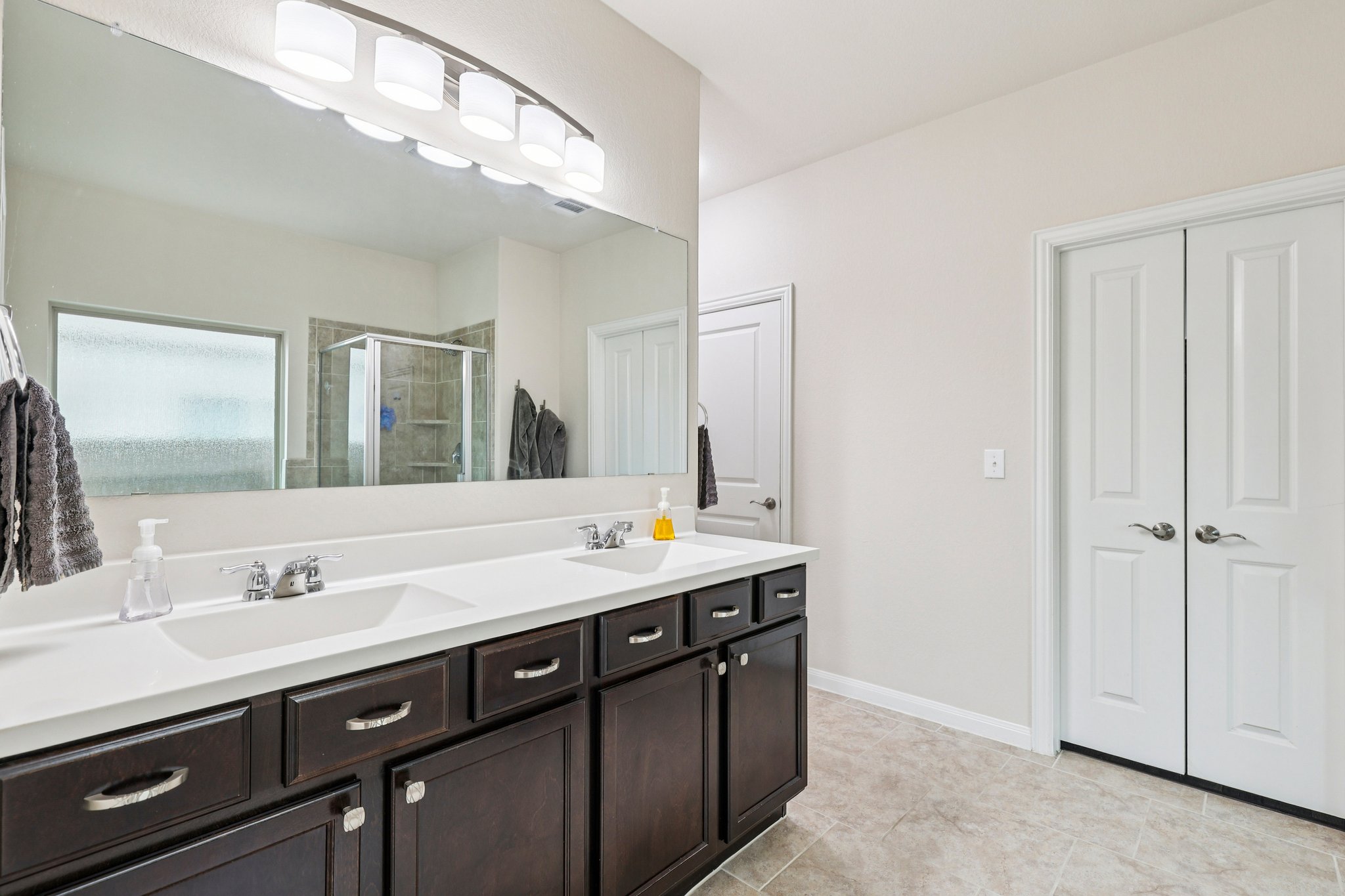 10033 Gertrudis Loop Austin, TX 78747 - Photo 28 of 39 Bathroom featuring a double vanity with dark wood cabinetry, white countertops, and dual sinks