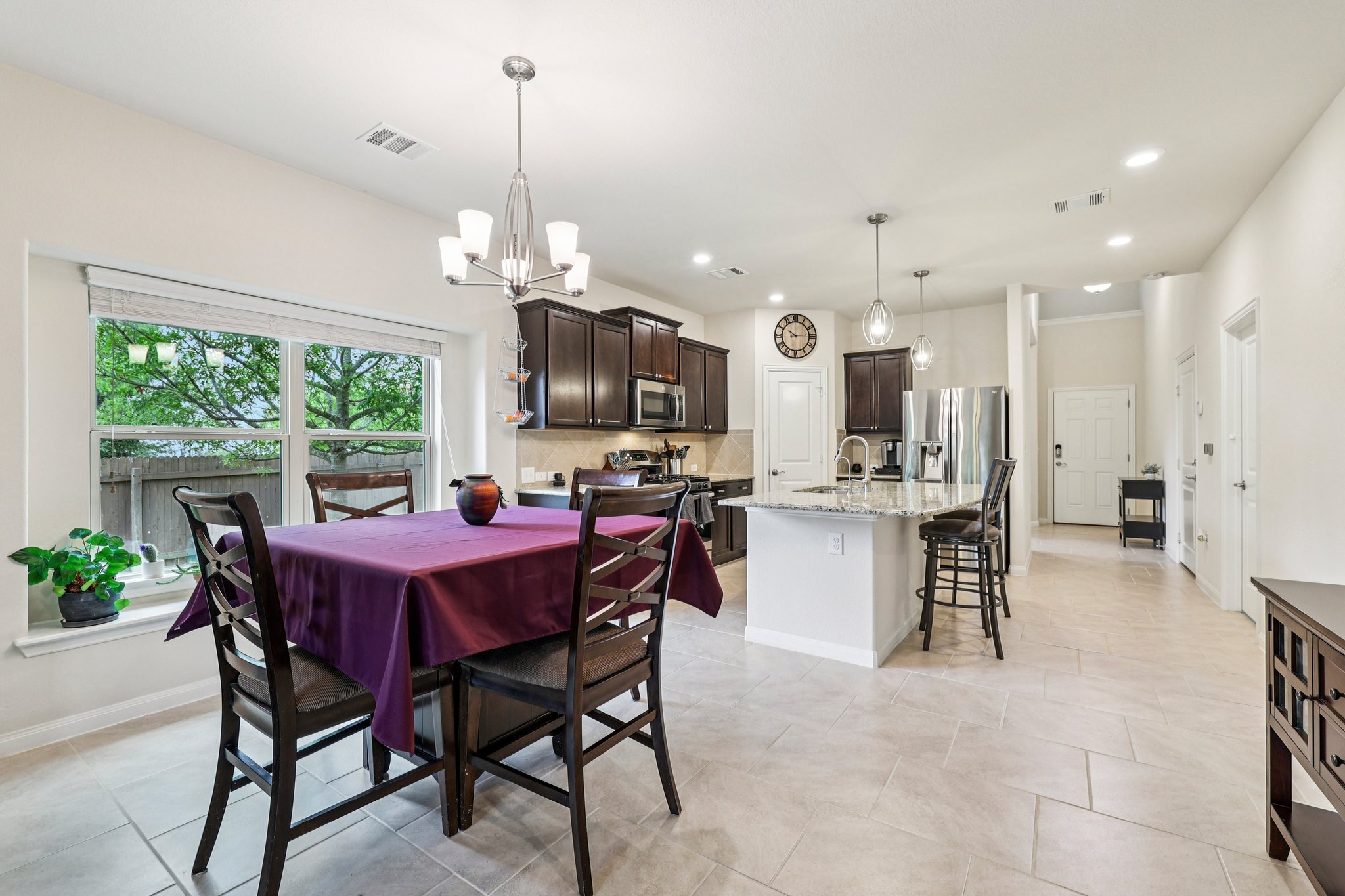 10033 Gertrudis Loop Austin, TX 78747 - Photo 30 of 39 Open concept kitchen and dining area featuring a kitchen island with seating, dark wood cabinetry, and stainless steel appliances
