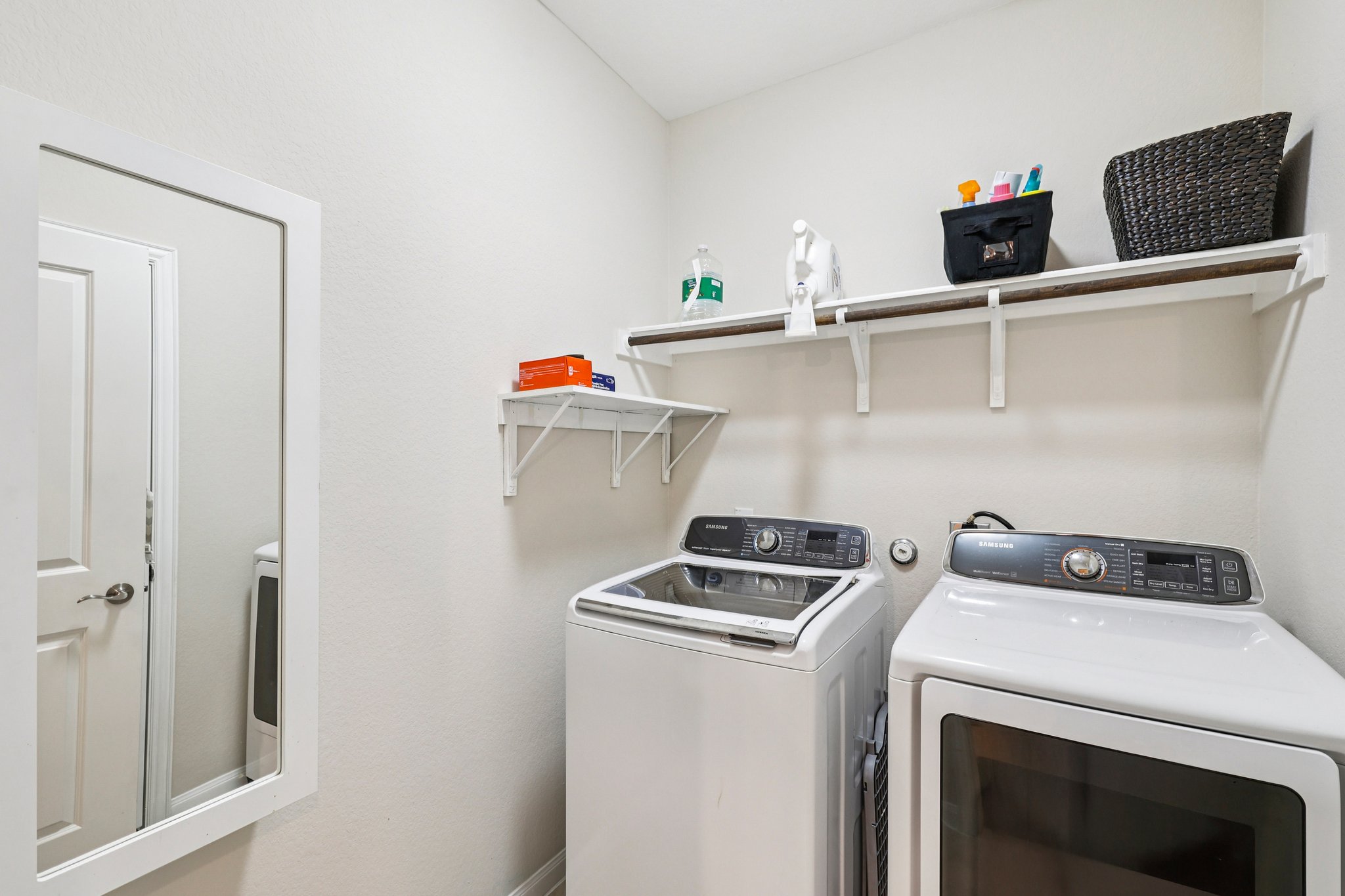 10033 Gertrudis Loop Austin, TX 78747 - Photo 34 of 39 This utility space features a washer and dryer, along with white wall-mounted shelving for storage