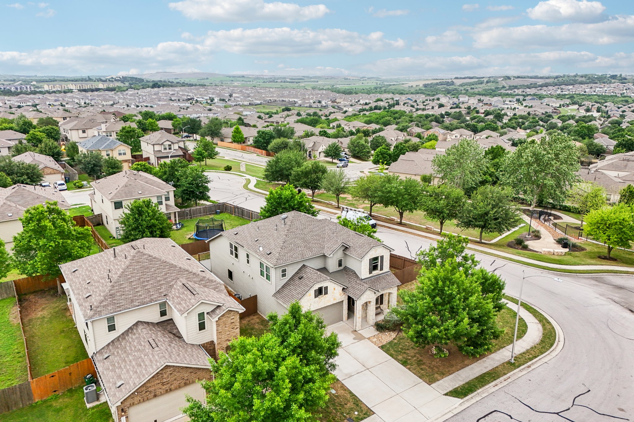 10033 Gertrudis Loop Austin, TX 78747 - Photo 4 of 39 Aerial view of the property and surrounding neighborhood, featuring tree-lined streets and residential homes with pitched roofs