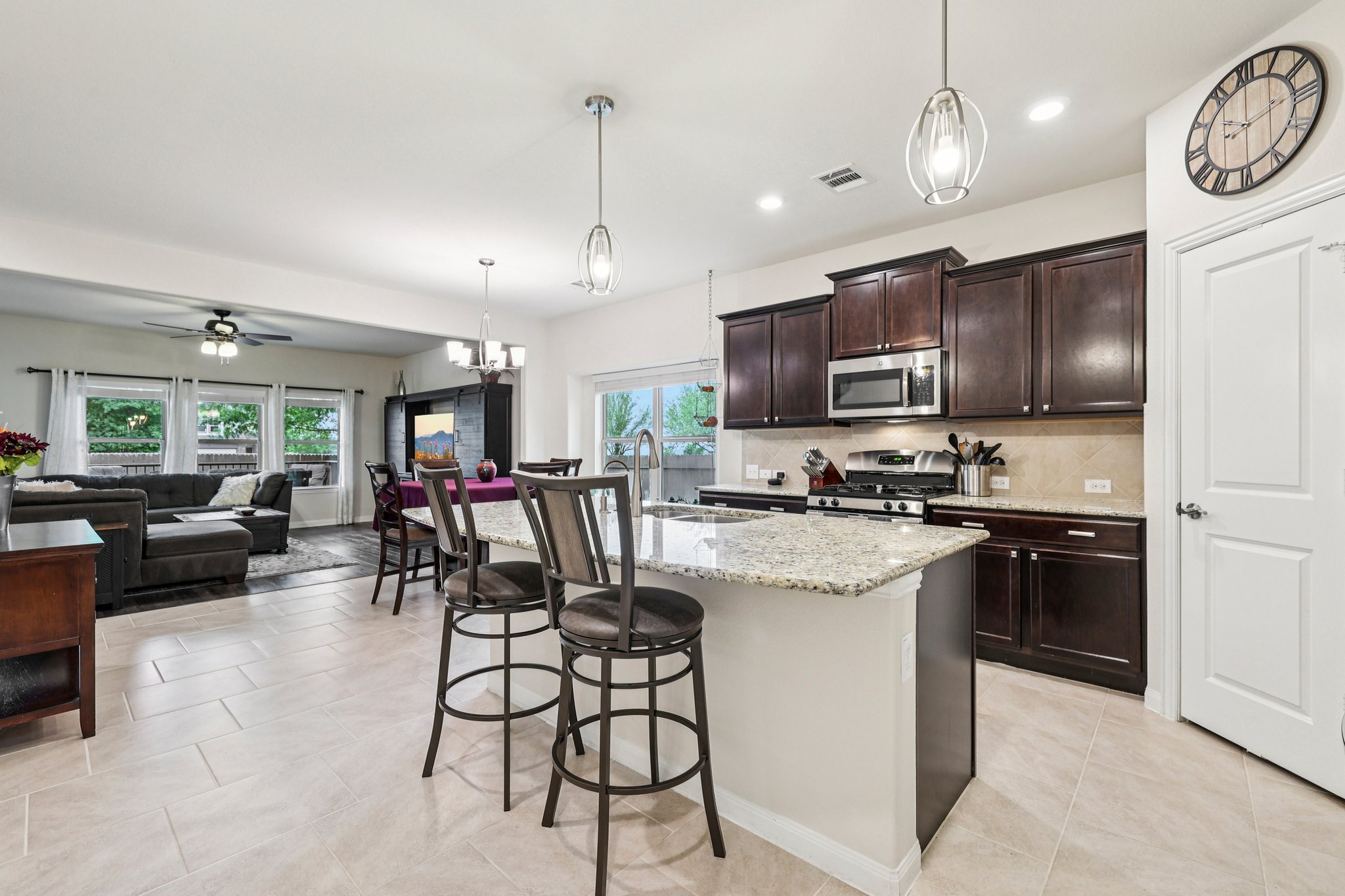 10033 Gertrudis Loop Austin, TX 78747 - Photo 5 of 39 The kitchen features dark wood cabinetry, stainless steel appliances, and a granite-topped island with seating