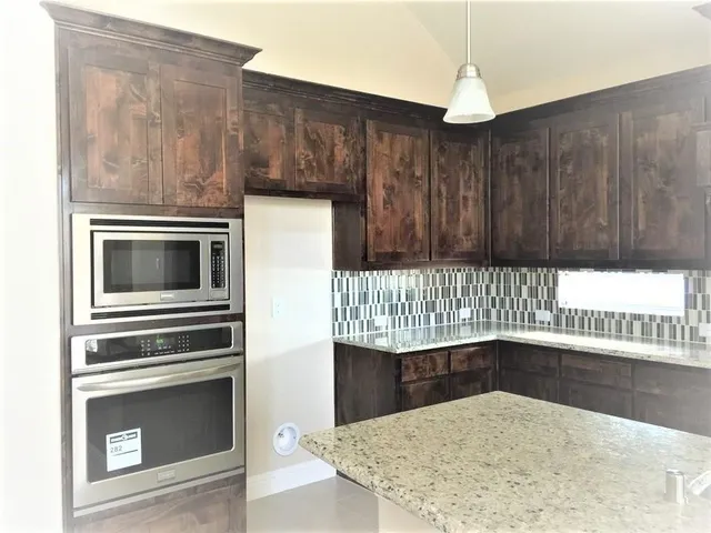 a kitchen with granite countertop a stove a microwave and a sink