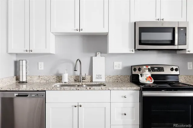 a kitchen with granite countertop white cabinets and stainless steel appliances