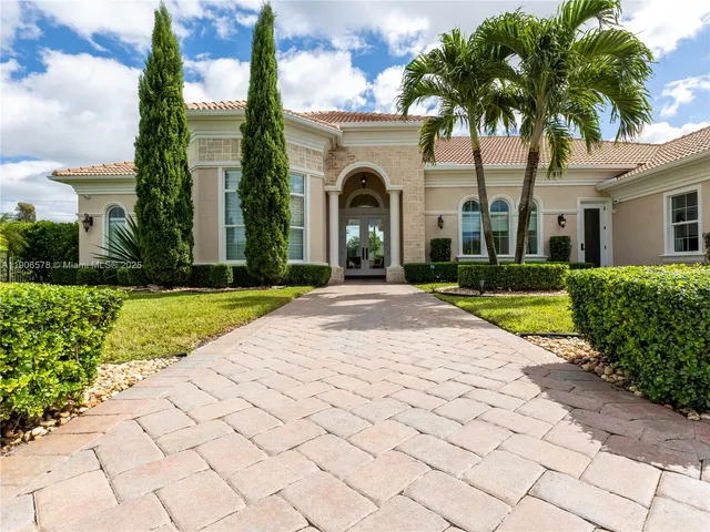 a view of a white house with a yard and potted plants
