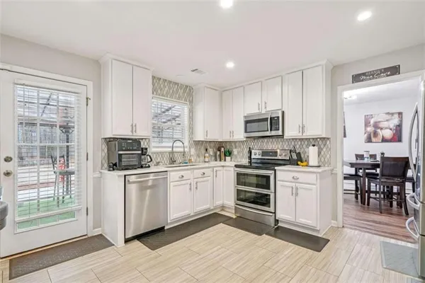 a kitchen with stainless steel appliances granite countertop a stove top oven a sink dishwasher a dining table and chairs with wooden floor