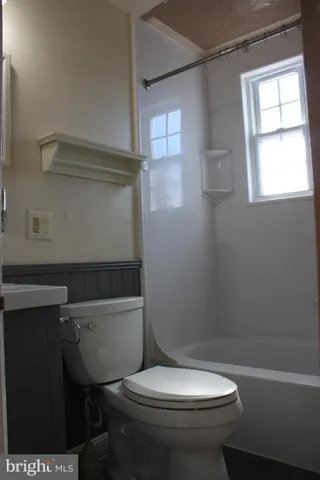 a white toilet sitting next to a bath tub