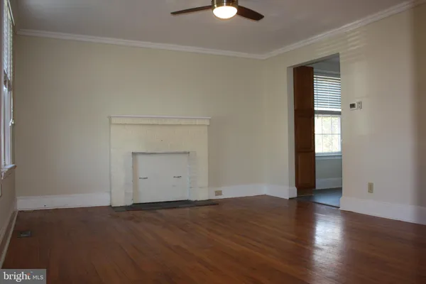 an empty room with wooden floor cabinet and windows