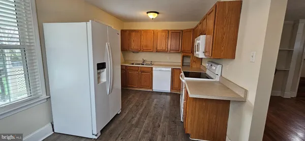 a kitchen with a refrigerator a stove top oven a sink and dishwasher with wooden floor