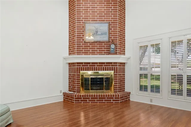 a view of an empty room with wooden floor and a fireplace