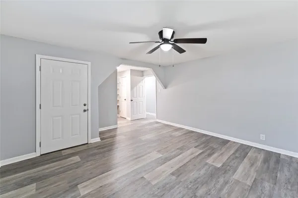 an empty room with wooden floor ceiling fan and windows