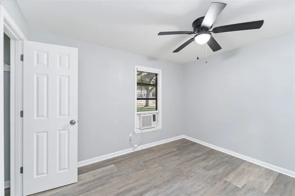 an empty room with wooden floor closet and windows