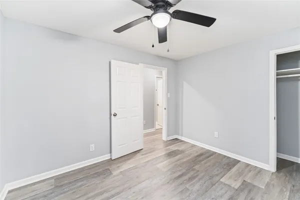 an empty room with wooden floor ceiling fan and window