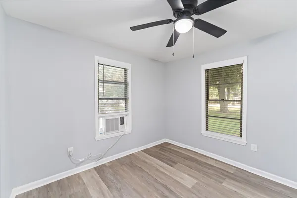 a view of an empty room with window and chandelier fan