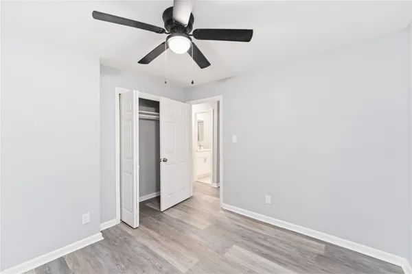 an empty room with wooden floor ceiling fan and window