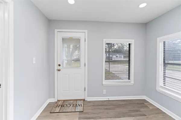 a view of an empty room with wooden floor and a window