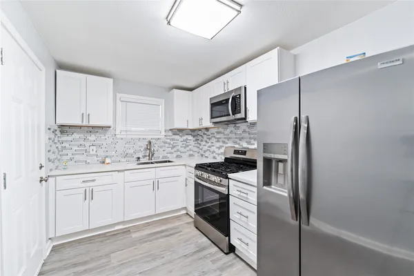 a kitchen with cabinets stainless steel appliances and sink