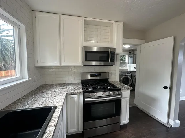 a kitchen with stainless steel appliances white cabinets and a stove top oven