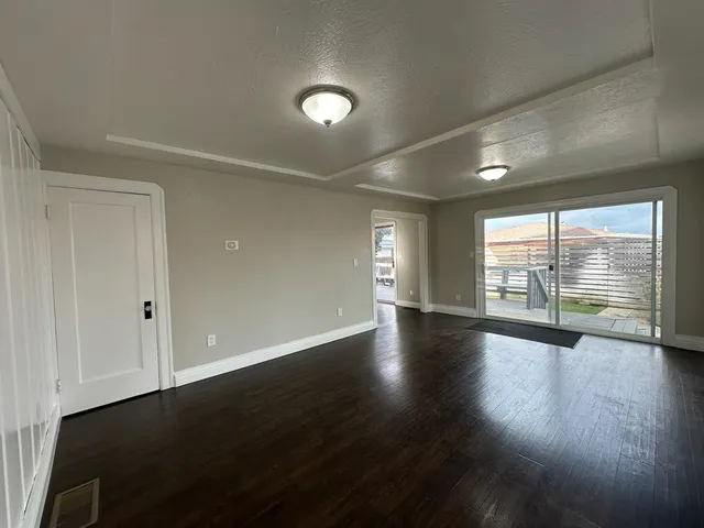 an empty room with wooden floor and windows with curtains