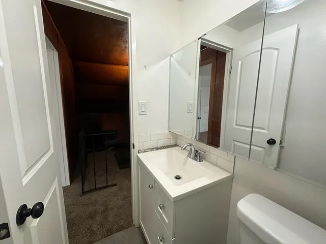 a bathroom with a sink and mirror with toilet