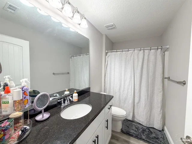a bathroom with a granite countertop sink toilet and a mirror