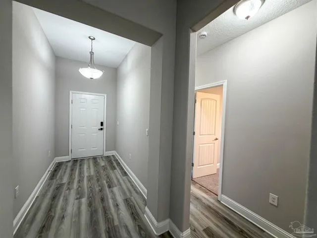 an empty room with chandelier fan and windows