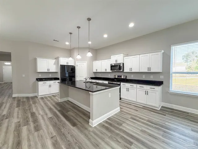 a large white kitchen with stainless steel appliances granite countertop a stove and a sink