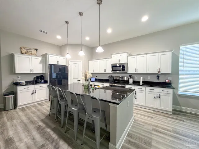 a kitchen with stainless steel appliances a stove a sink a refrigerator a center island and cabinets