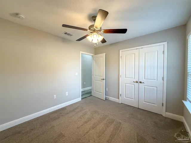 an empty room with windows and fan