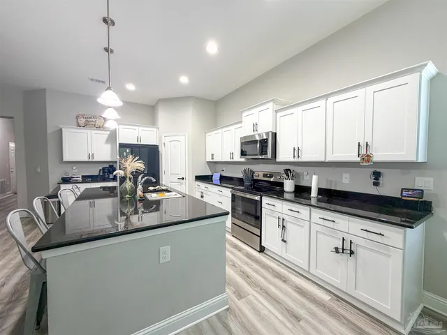 a kitchen with stainless steel appliances granite countertop a sink a stove a refrigerator a center island and cabinets