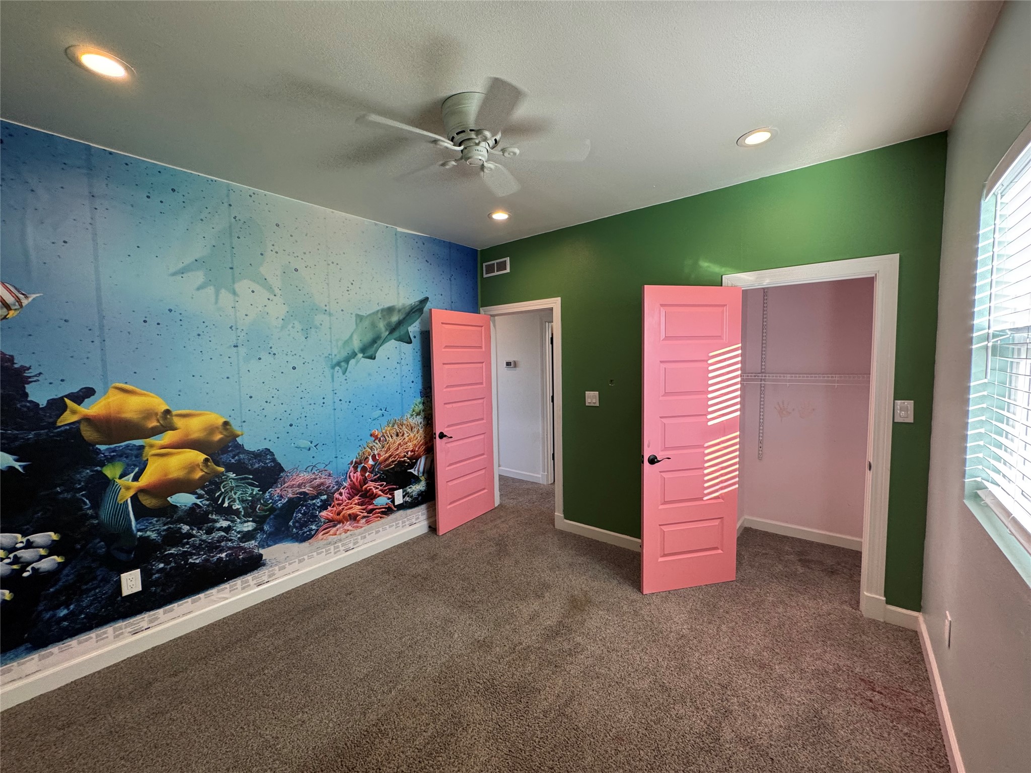 3633 Outback Trail Spicewood, TX 78669 - Photo 27 of 34 Unfurnished bedroom featuring an accent wall, ceiling fan, dark carpet, multiple windows, and recessed lighting