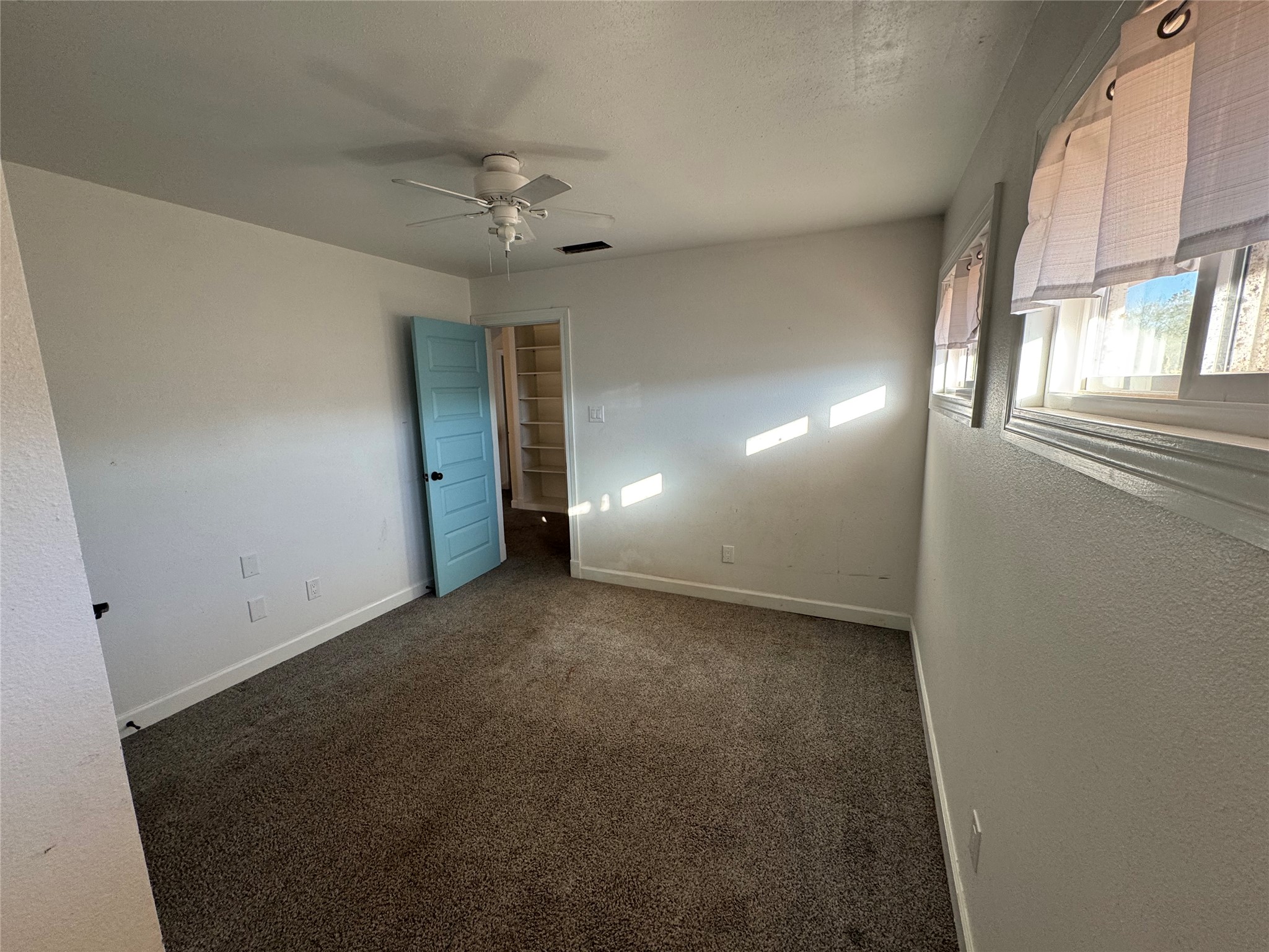3633 Outback Trail Spicewood, TX 78669 - Photo 33 of 34 Unfurnished room with dark colored carpet, a ceiling fan, and a textured wall